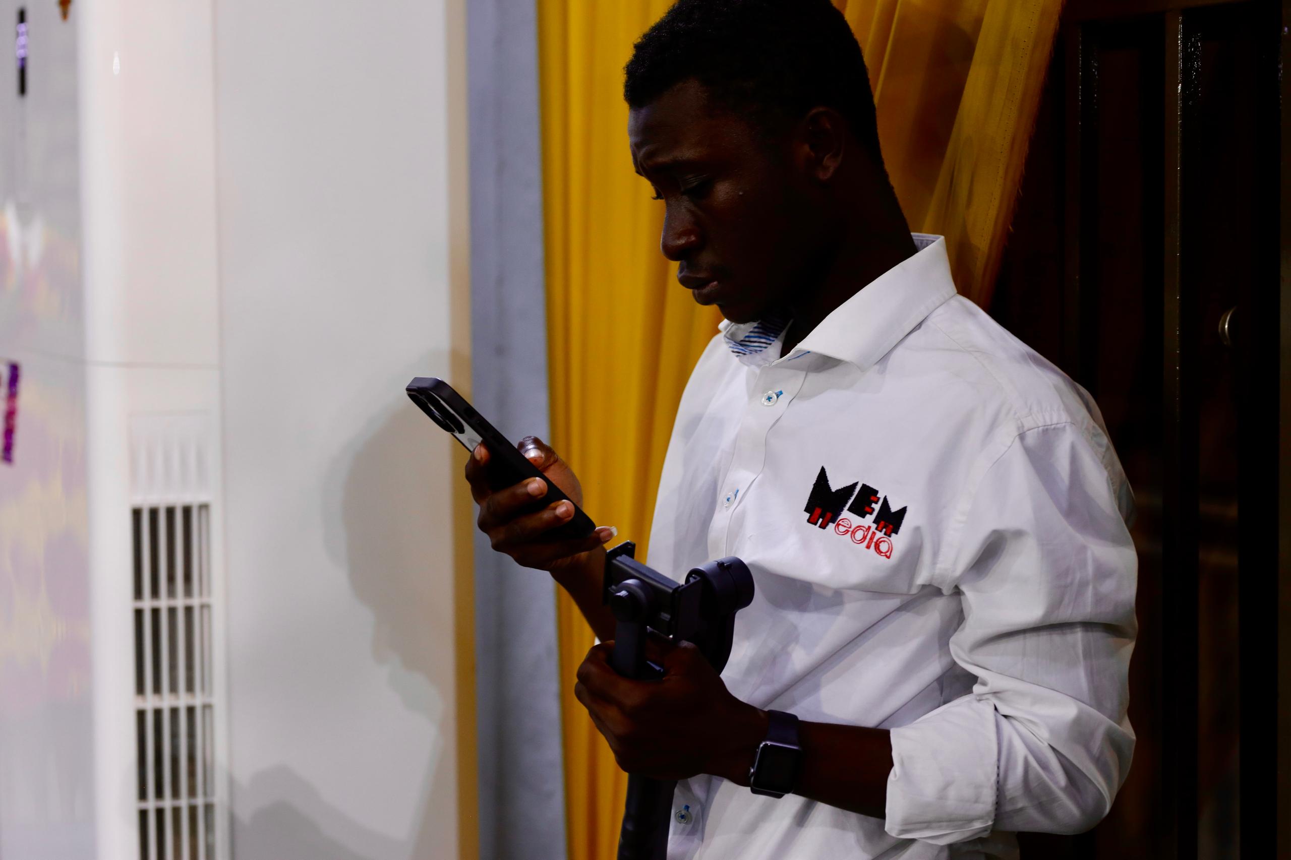 Mrr_Asiedu capturing a scene with his phone during a shoot